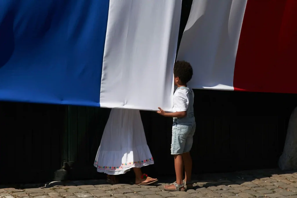 Le drapeau français porté par un adulte et un enfant, représentant l'intégration et l'aboutissement de la démarche de naturalisation française.